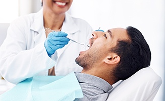 Man with brown hair in gray shirt undergoing dental exam