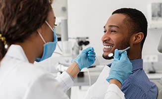 Man in checkered blue shirt smiling at dentist 