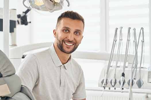 A smiling man sitting in a dental chair after his smile makeover