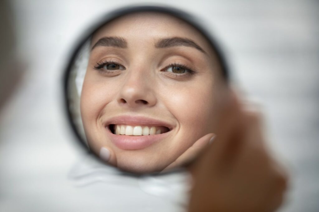 A woman looking at her teeth in the mirror.